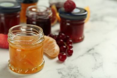 Jar of sweet jam on white marble table, closeup. Space for text