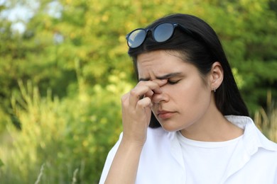 Young woman suffering from eyestrain outdoors on sunny day