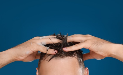 Man washing hair on blue background, closeup