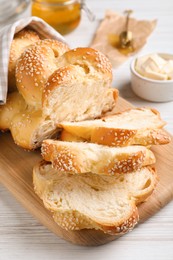 Cut freshly baked braided bread on white wooden table, closeup. Traditional Shabbat challah