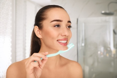 Woman holding toothbrush with paste in bathroom