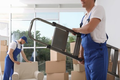 Moving service employees with ladder and cardboard boxes in room, closeup