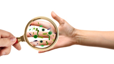 Woman with magnifying glass detecting microbes on hand against white background, closeup