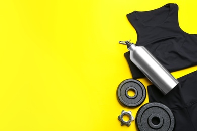 Flat lay composition with sportswear and equipment on yellow background, space for text. Gym workout