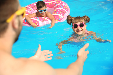 Father and children having fun in swimming pool, closeup. Family vacation
