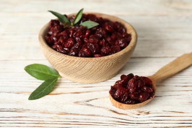 Photo of Tasty dried cranberries and leaves on white wooden table