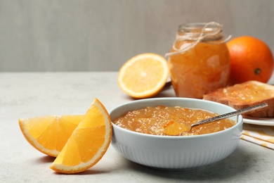 Delicious orange marmalade in bowl on light grey table. Space for text
