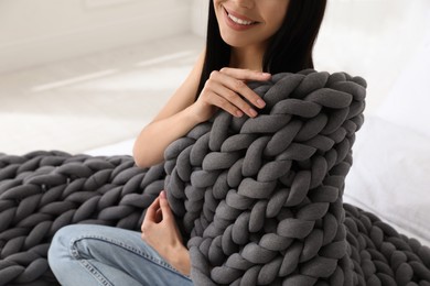 Woman with chunky knit blanket on bed at home, closeup