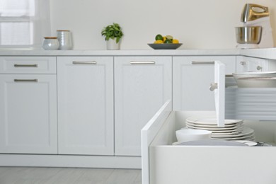 Photo of Open drawers with different plates and bowls in kitchen, space for text