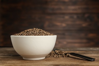 Ceramic bowl with chia seeds on wooden table, space for text. Cooking utensils
