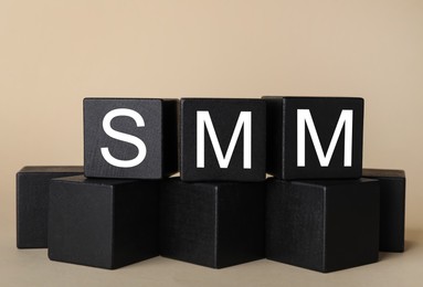 Black cubes with abbreviation SMM (Social media marketing) on beige background