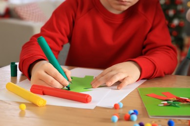 Little child making beautiful Christmas greeting card at home, closeup