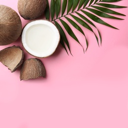 Fresh coconuts and palm leaf on pink background, flat lay. Space for text