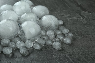 Photo of Many melting ice balls on dark grey table, closeup. Space for text