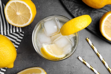Soda water with lemon slices and ice cubes on grey table, flat lay