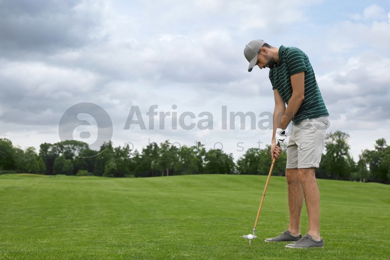 Photo of Man playing golf on green course. Sport and leisure