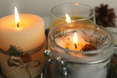 Burning scented conifer candles on table, closeup view