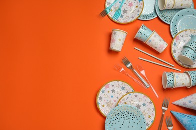 Disposable tableware on orange background, flat lay. Space for text