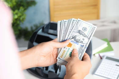 Photo of Woman holding money near counting machine indoors, closeup