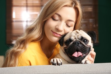 Woman with cute pug dog at home. Animal adoption