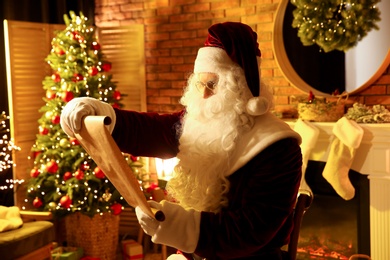 Santa Claus in glasses reading wish list indoors