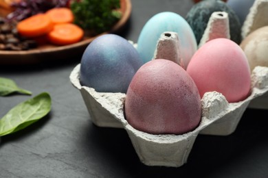 Photo of Easter eggs painted with natural organic dyes on black table, closeup. Space for text