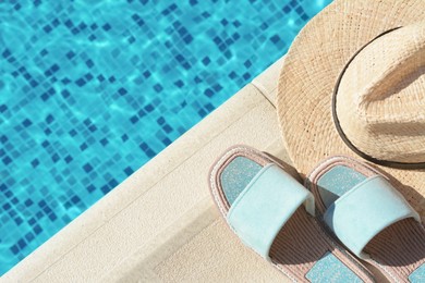 Photo of Stylish slippers and straw hat at poolside on sunny day, space for text. Beach accessories