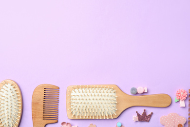 Flat lay composition with wooden hair brushes on violet background, space for text