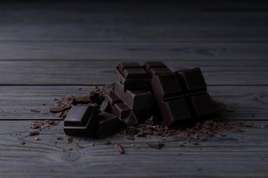 Pieces of delicious dark chocolate on wooden table