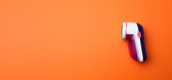 Photo of Modern fabric shaver on orange background, top view. Space for text