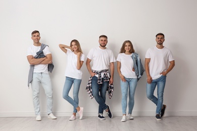 Group of young people in jeans near light wall