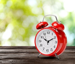 Red alarm clock on wooden table, space for text. Daylight saving time (Spring forward)