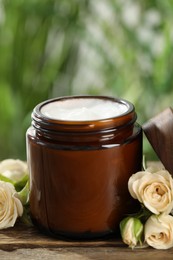 Photo of Jar of hand cream and roses on wooden table, closeup