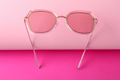 Photo of Stylish sunglasses on pink background. Summer accessory