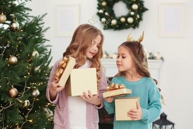 Photo of Cute little girls opening Christmas gifts at home