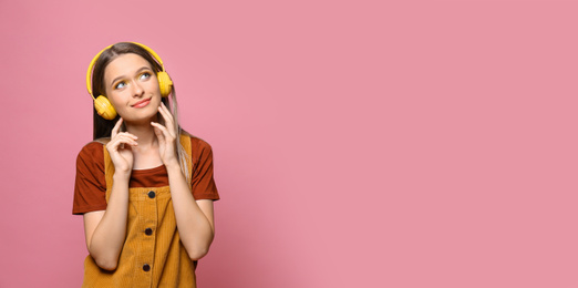 Young woman listening to music with headphones on pink background, space for text. Banner design