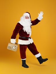 Santa Claus with vintage radio on yellow background. Christmas music