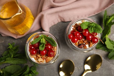 Delicious yogurt parfait with fresh red currants and mint on grey table, flat lay