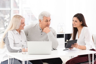 Mature couple discussing pension with consultant in office