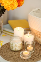 Beautiful burning candles, bag and flowers on table at home