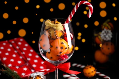 Christmas composition with tangerine pomander balls in wineglass against blurred lights