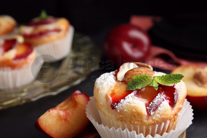 Delicious cupcakes with plums on black background, closeup