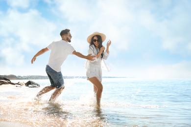Happy young couple having fun on beach near sea. Honeymoon trip