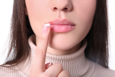 Young woman applying cold sore cream on lips, closeup