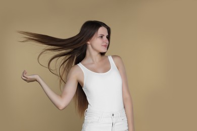 Photo of Young woman with strong healthy hair on beige background, space for text