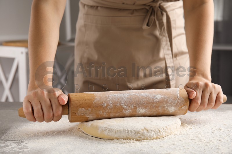 Woman rolling fresh dough at table, closeup