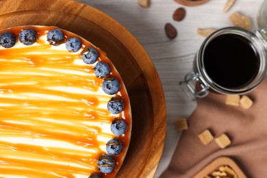 Delicious cheesecake with caramel and blueberries on white wooden table, top view. Space for text