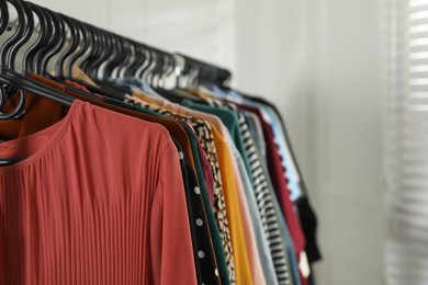 Rack with stylish clothes indoors, closeup. Fast fashion