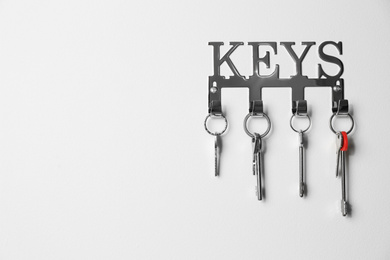 Metal key holder on light wall indoors. Space for text