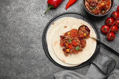 Tasty chili con carne with tortilla and ingredients on grey table, flat lay. Space for text